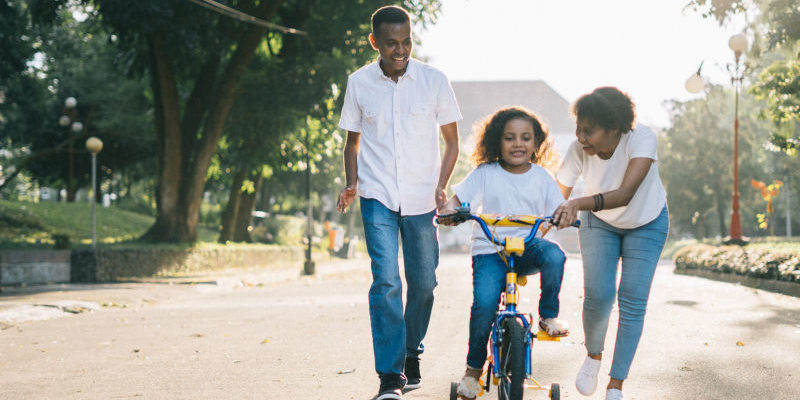 A Couple Protecting Their Child while Riding a Bike, Hudack Law Estate Planning Attorney