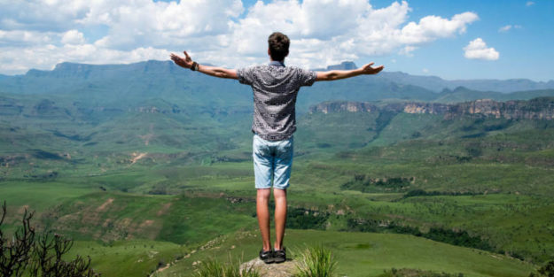 Young Man Standing on a Rock Facing the Hills and Mountains With White Open Arms, Corona Estate Planning Attorney.