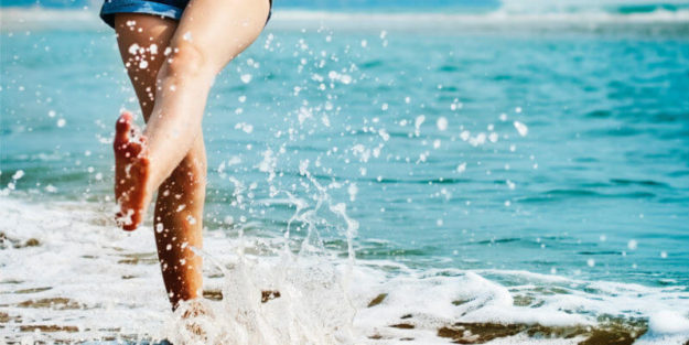 Woman on Vacation Kicking the Water on the Beach, Corona Estate Planning Attorney.