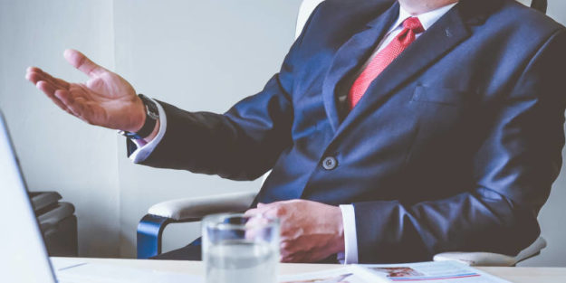 Probate Corona Estate Planning Attorney on a Blue Suit Behind a Desk Explaining Probate Avoidance Strategies.