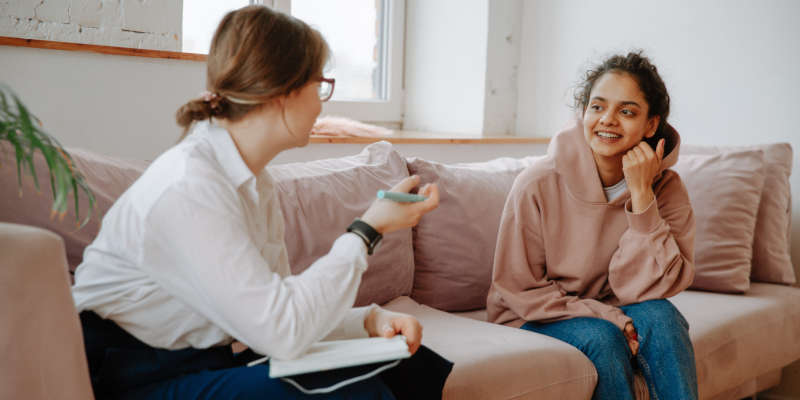 A Young Woman Talking With an Corona Estate Planning Attorney on a Sofa About Health Care Proxy.