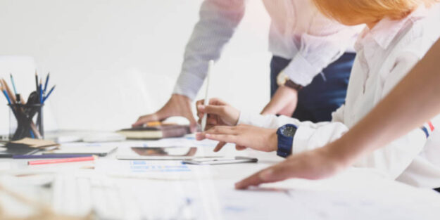 Corona Estate Planning Attorney in White Long Sleeve Shirt Using a Tablet Computer Holding Stylus on a White Table.
