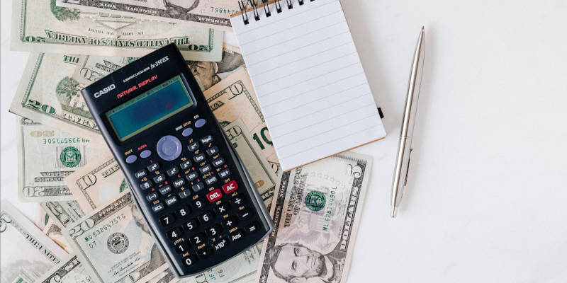 A Calculator and Notepad Placed Over a Stack of Usa Dollars, Corona Estate Planning Attorney.